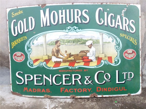 A turquoise enamel advertising sign for Gold Mohurs Cigars, with an illustration of two workers making cigars